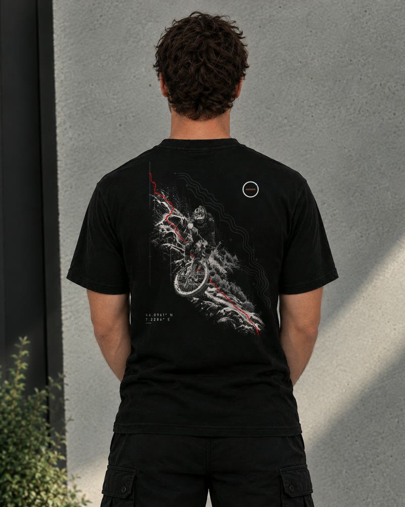 A man wearing the black Descent tee, back view, a rider dropping down a trail